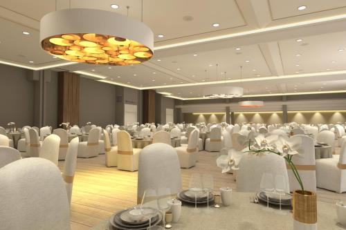 a banquet hall with white chairs and tables and a chandelier at Hotel Guadalajara & Conference Center Affiliated by Meliá in Guadalajara