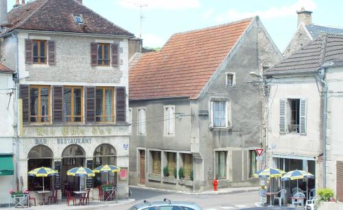un grupo de edificios con mesas y sombrillas en una calle en Les Epis d'Or, en LʼIsle-sur-Serein