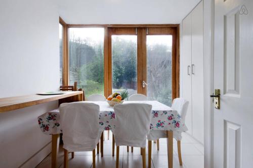 een keuken met een tafel met witte stoelen en een raam bij Emirates-Arsenal in Londen