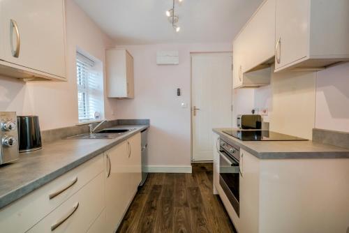 a kitchen with white cabinets and a wooden floor at Cannock Hotel Apartments in Cannock