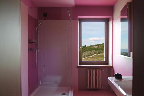 un bagno rosa con servizi igienici e finestra di La Grande Casa Valpolicella a SantʼAmbrogio di Valpolicella