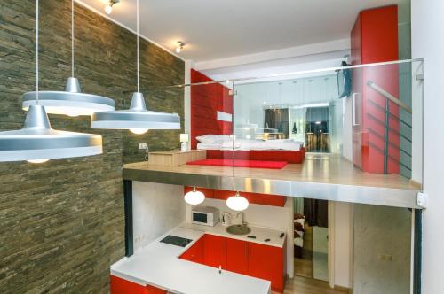 a kitchen with red cabinets and a sink and lights at VIP Apartment at Horodetskoho 4 in Kyiv