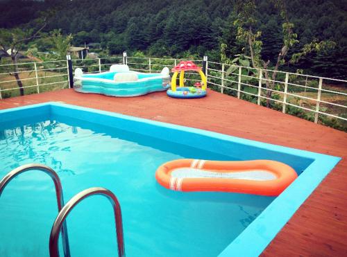 ein Pool mit zwei Schlauchbooten und einem Spielplatz in der Unterkunft Walking Sky Pension in Gapyeong