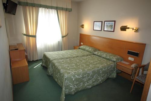 a hotel room with a bed and a window at Hotel Ramos in Silleda
