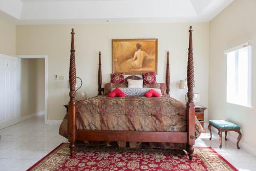 モンテゴ・ベイにあるThe Royal Kensington Villa 4の壁に絵が飾られたベッドのある寝室