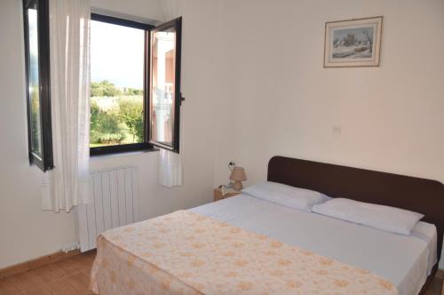 a bedroom with a bed and a large window at Franko Apartmani in Zambratija