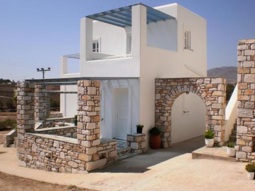 Casa blanca con pared de piedra y arco en Panorama en Piso Livadi
