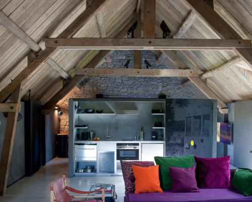 Il comprend un salon avec un canapé violet et une cuisine. dans l'établissement La Micheline-Design House Maredsous, à Bioul