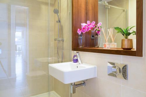 a bathroom with a sink and a shower with pink flowers at Exquisite & Homely Penthouse, 2 mins walk from Cambridge Station, Big balcony, lift access, secured gated on-site parking, self check-in & SUPER Fast WIFI in Cambridge