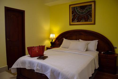 a bedroom with a bed with a red bag on it at Hotel Perla Verde in Volcán Chimborazo