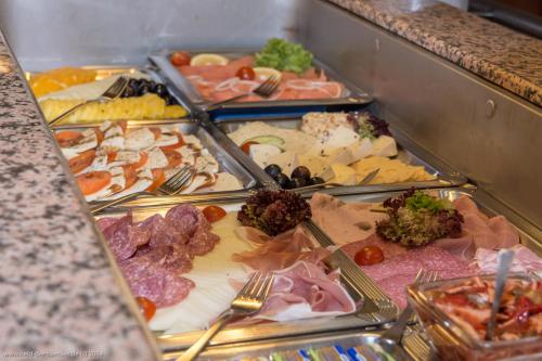 een buffet met verschillende soorten eten op dienbladen bij Hotel Lindwurm in Bad Goisern