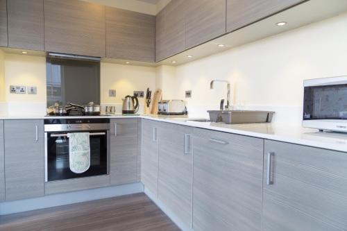 a kitchen with gray cabinets and a sink at Contemporary & Homely Penthouse, 2 mins walk from Cambridge Station, lift access, secured gated on-site parking, self check-in, SUPER Fast WIFI, Terrace & Sleeps 6 in Cambridge