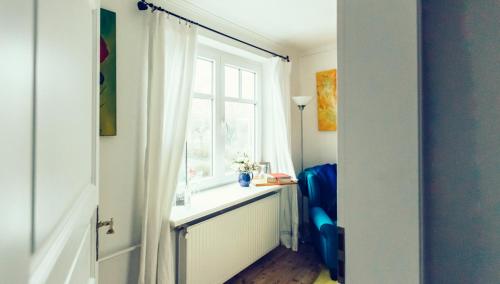 Cette chambre dispose d'une fenêtre et d'une chaise bleue. dans l'établissement Das Blaue Haus, à Husum