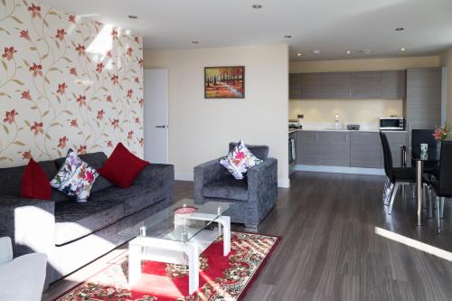 a living room with a couch and chairs and a kitchen at Contemporary & Homely Penthouse, 2 mins walk from Cambridge Station, lift access, secured gated on-site parking, self check-in, SUPER Fast WIFI, Terrace & Sleeps 6 in Cambridge