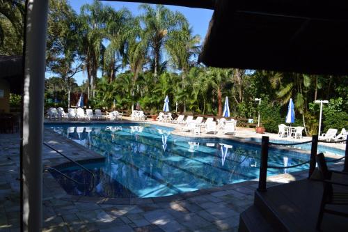 a large swimming pool with white chairs and umbrellas at Riviera de São Lourenço Flat in Riviera de São Lourenço