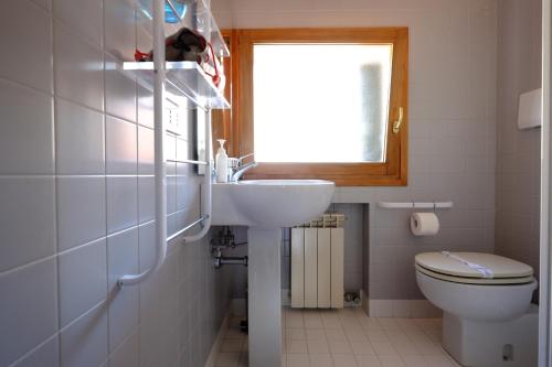 Un baño con lavabo, inodoro y ventana. en Mansardina San Marco, en Venecia
