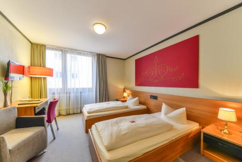 a hotel room with two beds and a desk at Hotel Fidelio in Munich