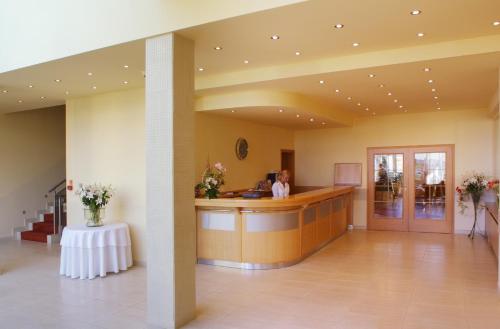 a woman standing at a reception desk in a lobby at Hotel Bielany in Bielany Wrocławskie