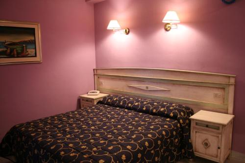 a bedroom with a bed and two lights on the wall at Hotel Marini in Sassari