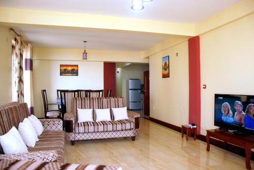 a living room with couches and a flat screen tv at Kigali Village Suites in Kigali