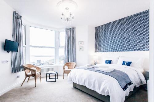 a white bedroom with a large bed and a chair at No4 St Ives in St Ives