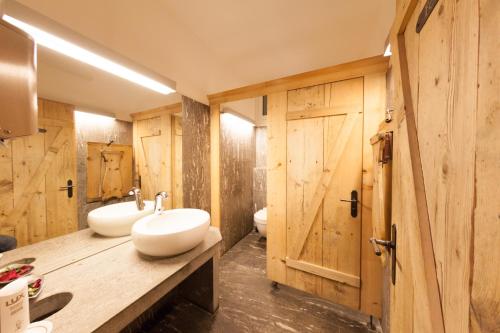 two sinks in a bathroom with wooden walls at Familienhotel Alpina in Breil/Brigels