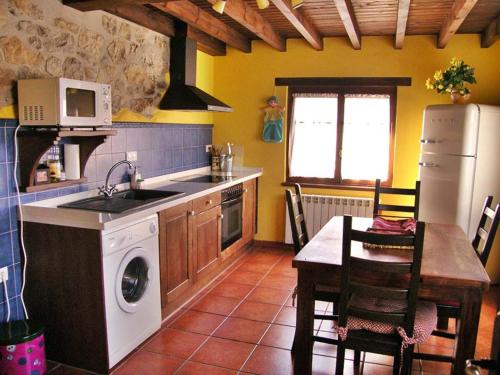 a kitchen with a stove and a sink and a table at Apartamentos Rurales la Candaliega in Cangas de Onís