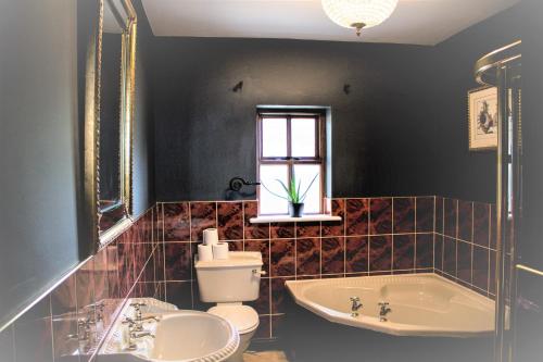 een badkamer met een bad, een toilet en een wastafel bij Storytellers Cottage in Upper Ballycotteen