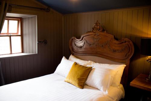 una camera da letto con letto, testiera e cuscini in legno di Storytellers Cottage a Upper Ballycotteen