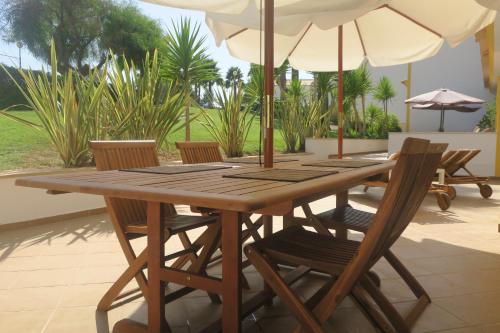 a wooden table with chairs and an umbrella at Condominio Cerro da Guia in Guia