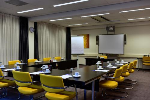 a conference room with tables and yellow chairs and a screen at Onderwijshotel De Rooi Pannen Eindhoven in Eindhoven