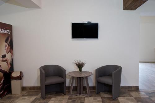 dwa krzesła i stół i telewizor na ścianie w obiekcie Bella Jūrmala Hotel w Jurmale