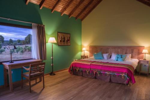 a bedroom with a bed and a desk and a window at Lago Rosario Lodge in Trevelin