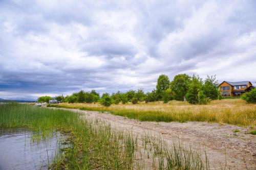 a dirt road next to a body of water at Lago Rosario Lodge in Trevelin