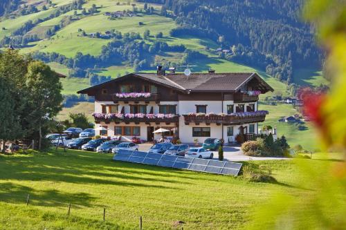 a house on a hill with cars parked in a field at Pension Schwab in Taxenbach