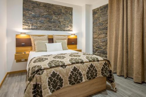 a bedroom with a bed and a stone wall at Enxurros House in Ponta Delgada