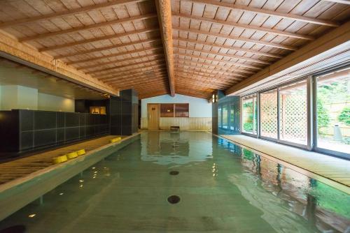 an indoor pool with a wooden ceiling and glass windows at Nishiizu Crystal View Hotel in Nishiizu