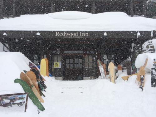 a snow covered building with skis in the snow at Spa Lodge Redwood Inn in Takayama