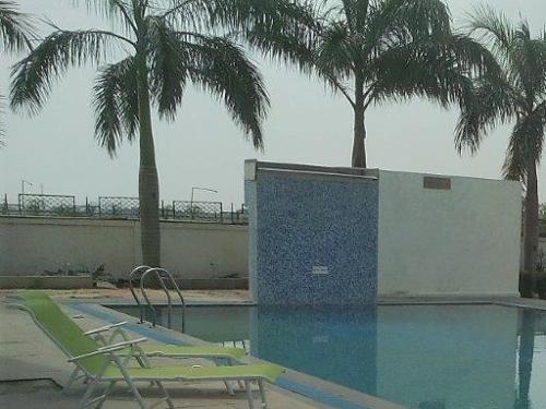 a swimming pool with two chairs and palm trees at Comfort Inn Donil Vadodara in Vadodara