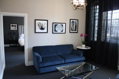 a living room with a blue couch and a glass table at Mrs Banks Hotel in Sydney