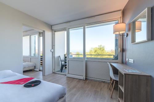 ein Schlafzimmer mit einem Bett und einem Schreibtisch mit einem Fenster in der Unterkunft Village Vacances Azureva Anglet in Anglet