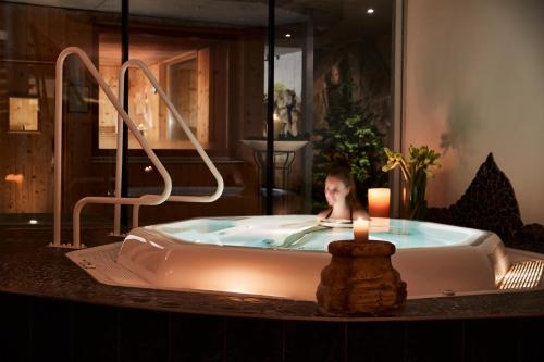 a woman in a bath tub with a candle in it at Alpenhotel St.Christoph in Sankt Christoph am Arlberg