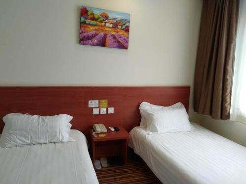 a hotel room with two beds and a telephone at Goldmet Inn Beojing Capital Airport Xinguozhan in Shunyi