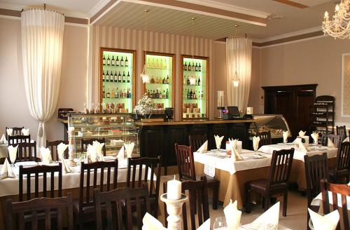 un restaurante con mesas y sillas blancas y un bar en Valdi Classic, en Zabrze
