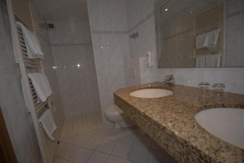 łazienka z 2 umywalkami, toaletą i prysznicem w obiekcie Hotel Auf dem Kamp w mieście Hagen