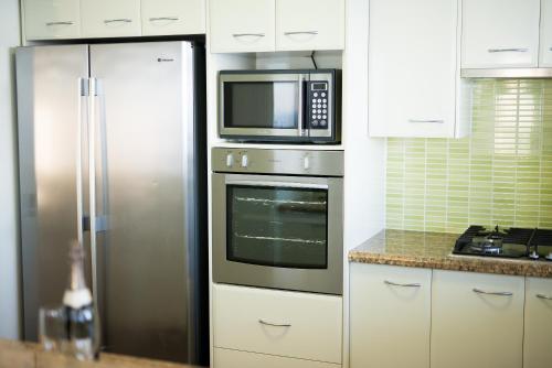 a kitchen with a stainless steel refrigerator and a microwave at Xanadu Resort in Gold Coast