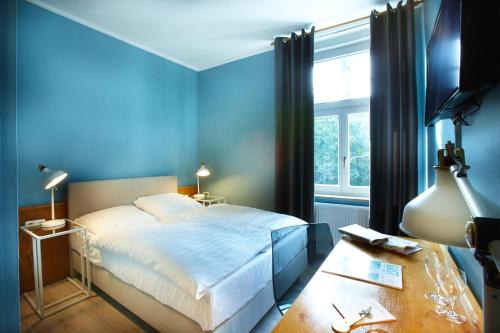 a blue bedroom with a bed and a table at Hotel Pelli Hof Rendsburg by Tulip Inn in Rendsburg