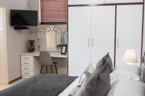 a bedroom with a bed and a desk with a computer at A' Queenslin Guesthouse in Paarl