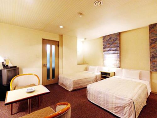 佐世保市にあるレオ プラザ ホテルのベッド2台とテーブルが備わるホテルルームです。