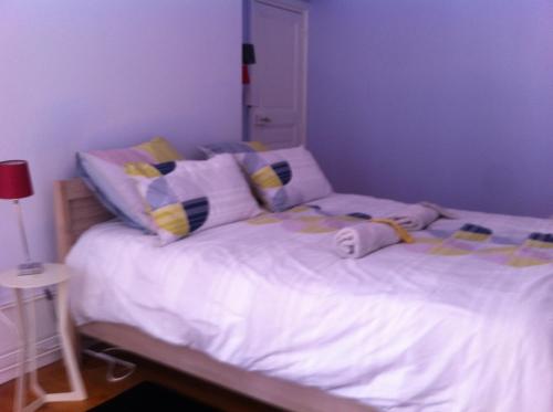 une chambre avec un lit avec des draps blancs et des oreillers dans l'établissement Le Nid De La Chouette, à Dijon